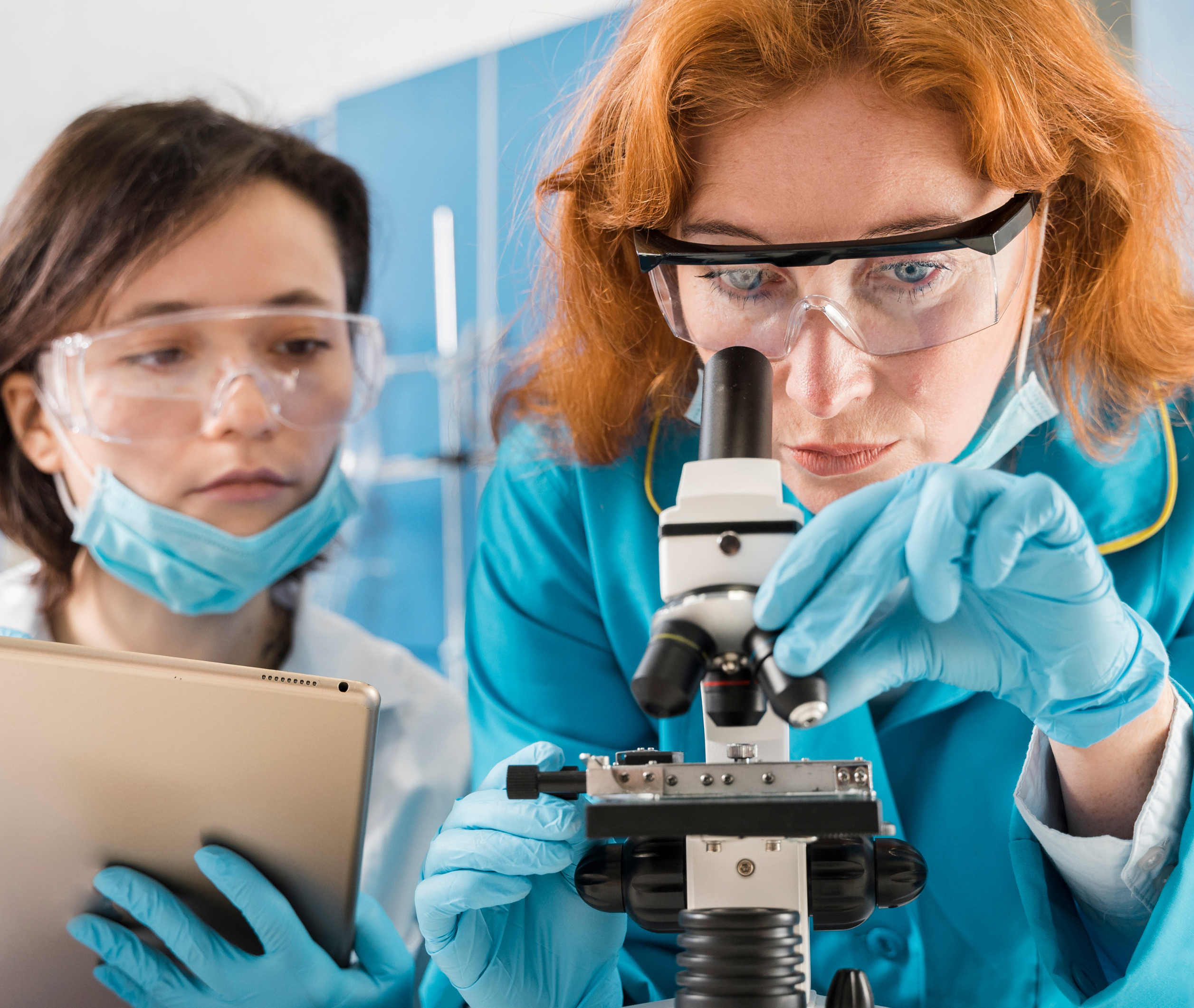 duas cientistas mulheres olhando microscopio técnicos em analises clinicas